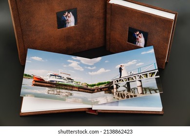 Wedding Photobooks In Brown Leather Binding With Photos On The Cover. High-quality And Expensive Photo And Printing Products. Services Of A Professional Photographer And Designer. On Black Background