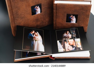 Wedding Photobooks In Brown Leather Binding With Photos Of On The Cover. High-quality And Expensive Photo And Printing Products.services Of A Professional Photographer And Designer.on Black Background