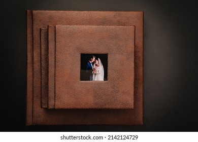 Wedding Photobooks In Brown Leather Binding With Photos On The Cover. High-quality And Expensive Photo And Printing Products. Services Of A Professional Photographer And Designer. On Black Background