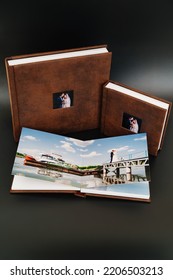 Wedding Photobooks In Brown Leather Binding With Photos On The Cover. High-quality And Expensive Photo And Printing Products. Services Of A Professional Photographer And Designer. On Black Background