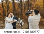 wedding photographer taking pictures of the bride and groom on the wedding day in autumn