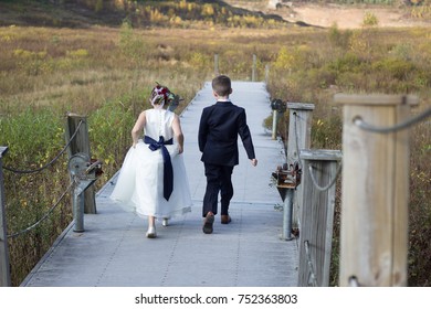 Wedding Photography Flower Girl And Ring Bearer Walking Down A Dock Surrounded By A Meadow And Trees