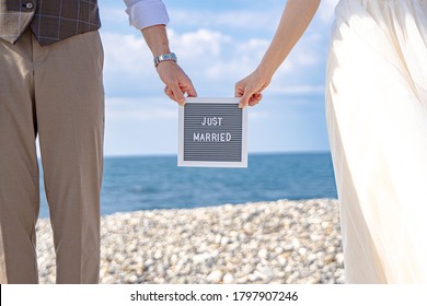 Wedding photos. A couple with a wedding board at the sea.