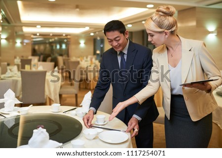 Wedding planner and banquet manager discussing table setting