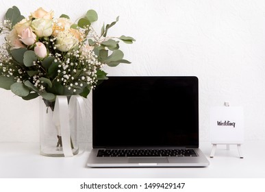 Wedding Planning Concept. Woman Home Office Desk With Laptop And Roses Bouquet On White Background