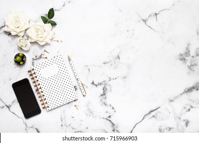 Wedding Planning Flat Lay On Marble Table Top With White Roses, Mobile Phone, Notebook And Pen