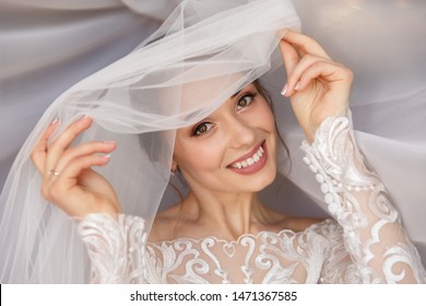 Wedding portait of happy bride. Gorgeous beauty young bride portrait. Beautiful bride with wedding makeup in white wedding veil. Bridal fashion model posing in interior.