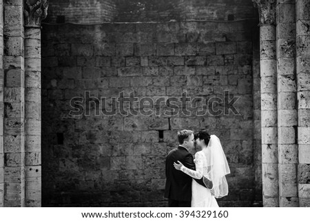 Wedding portrait of stylish happy kissing newlyweds outdoors