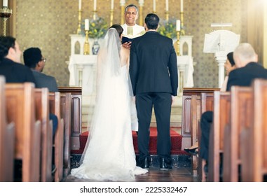 Wedding, priest and couple at the altar for marriage vows in commitment ceremony in a church from behind. Married, love and caring bride and groom celebrating their loving relationship in a chapel