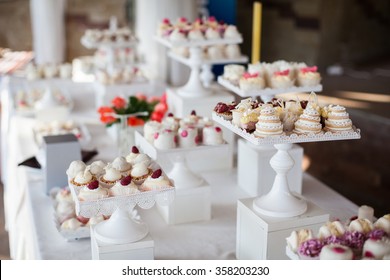 Wedding reception dessert table with delicious decorated white cupcakes with frosting closeup
