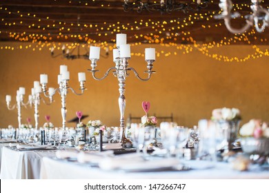 Wedding reception hall with decor including candles, cutlery and crockery; selective focus on candelabra
