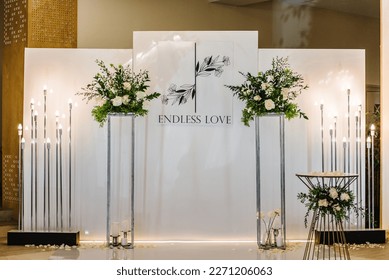 Wedding reception for luxury ceremony. Copy space. Celebration concept. Photo-wall, arch place decorated candles and flowers, greenery. Trendy decor for wedding party in the banquet area.