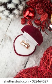 Wedding Ring Among Christmas Decorations On Wood Background.