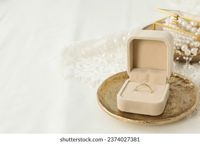 Wedding ring in case on light background, space for text