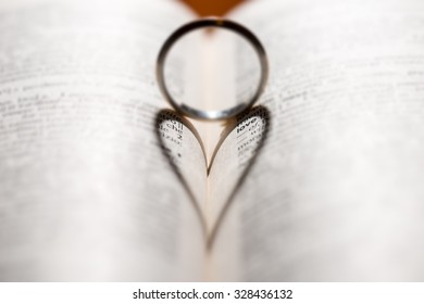 Wedding ring casting a heart-shaped shadow on the book page