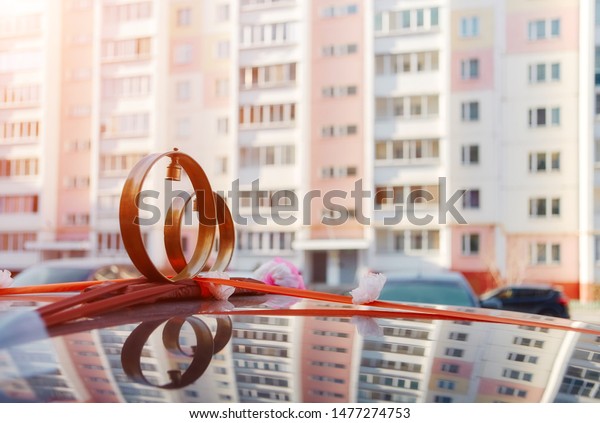 Wedding rings with bells on the roof of the car,\
against the background of urban buildings. Traditional Russian\
decoration of a wedding\
convoy.