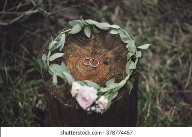 Wedding rings inside a flower headband on a wooden stump - Powered by Shutterstock