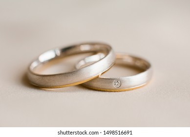 Wedding rings lie on greyish beige . Close up.