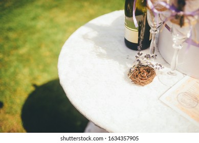 Wedding rings in a little decorative nest with a sprig of lavander on the white, round table. Close up, outoor wedding conception. - Powered by Shutterstock