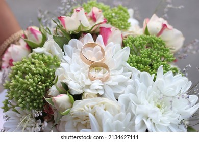 Wedding rings on a wedding bouquet with chrysanthemums and roses. Gifts and flowers for a festive feast from guests for the bride
