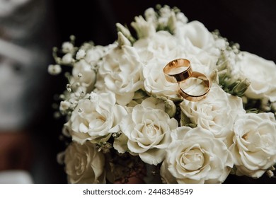 Wedding rings on the wedding bouquet of white roses. - Powered by Shutterstock