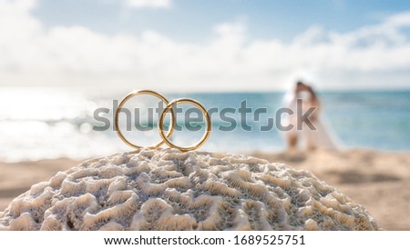 wedding rings on a coral in front of the sea. With a couple on a backgroud