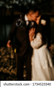 Wedding Rings On A Fly Fishing Hook With Couple Behind Out Of Focus In Blur