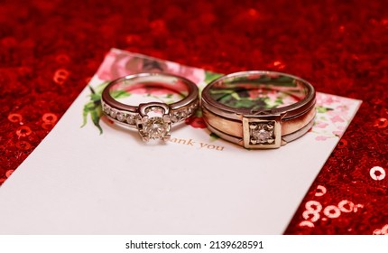 Wedding Rings On Glitter Red Background.  Modern Wedding Ring. Beautiful Wedding Or Engagement Ring Symbol.