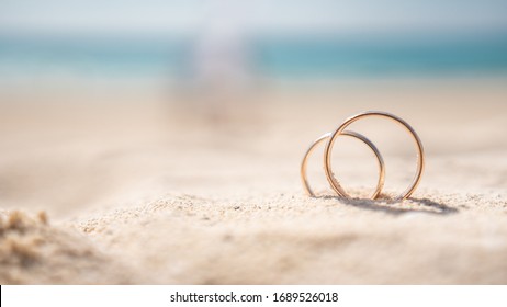 wedding rings on a send in front of the sea. - Powered by Shutterstock