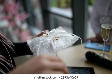 Wedding Rings On A White Pad, Close-up. The Master Of Ceremonies Holds A White Pillow With Wedding Rings In His Hands