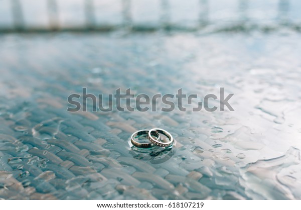 Wedding rings on the window in the rain. Drops on\
the glass. Testury water\
glass.