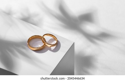 Wedding rings on a wooden box with shadows of leaves - Shutterstock ID 2045446634
