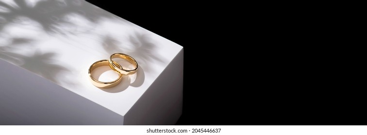 Wedding rings on a wooden box with shadows of leaves - Shutterstock ID 2045446637