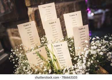 wedding seating plan displayed on cards with a bunch of white flowers