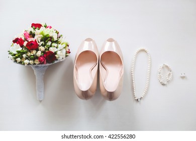 Wedding shoes cream color on a white table. Earrings. Bracelet. Necklace. The bride's bouquet.