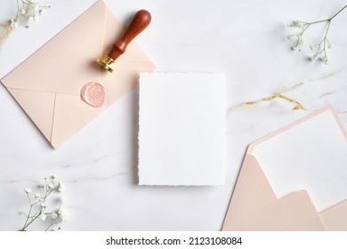 Wedding stationery set on marble desk top view. Blank paper card mockup, pastel pink envelopes with wax seal stamp, gypsophila flowers. - Shutterstock ID 2123108084