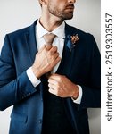 Wedding, suit and flower with man getting ready closeup in studio on white background. Marriage, celebration and style with confident groom dressing with attitude, necktie and clothes for fashion