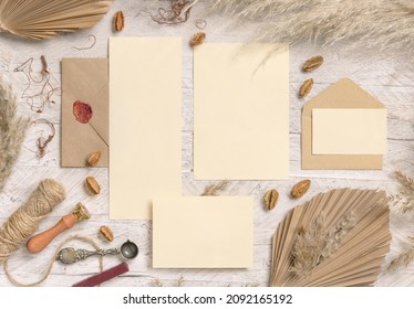 Wedding suite cards and envelope near dried plants, palm leaves and pampas grass top view. Boho scene with blank paper cards flat lay. Wedding set cards mockup, place for text