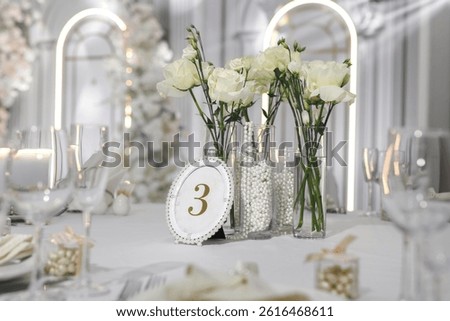 Wedding table decor. Live roses, candles and a table number plate for the guests