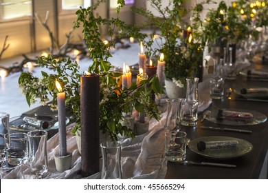  Wedding table decorated with candles, served with cutlery and crockery and covered with a tablecloth. Banquet dinner party with magic gift on plate