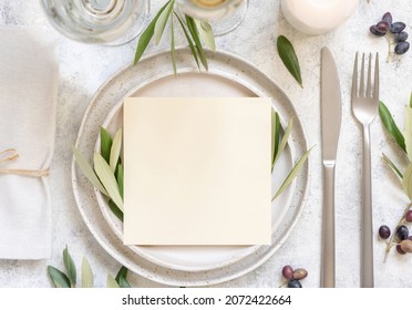 Wedding Table place with invitation card and porcelain plates decorated with olive branches top view. Elegant modern template with square blank paper card flat lay. Mediterranean mockup, copy space - Powered by Shutterstock