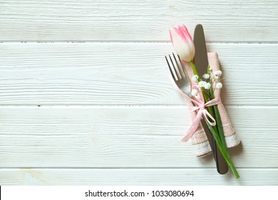 Wedding table setting composition with fork & knife silverware, pink tulip tied with pink ribbon on white wooden texture table background. Happy easter greeting card. Close up, top view, copy space. - Powered by Shutterstock