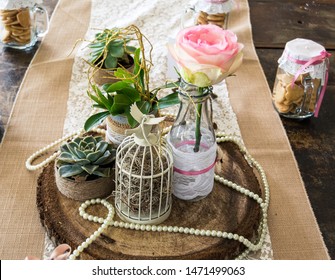 A wedding table setting, rustic style with a rose, succulent plant and string of pearls.