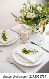 Wedding teble decoration with white flowers, glasses and white napkins. Elegantly decorated table at a wedding reception. Festive table setting. The wedding decor. 