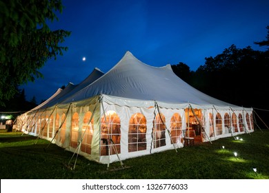 A wedding tent at night with blue sky and the moon. The walls are down and the tent is set up on a lawn - wedding tent series