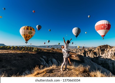 Wedding travel. Honeymoon trip. Couple in love among balloons. A guy proposes to a girl. Couple in love in Cappadocia. Couple in Turkey.  Man and woman traveling. Festival of balloons. Tourists