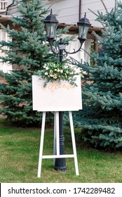 Wedding White Board Mockup Easel With Welcome Sign Decorated With Flowers, Outdoors. Greeting Card Template