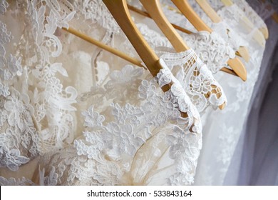 Wedding white dresses hanging on a hanger. Fashion look. Wedding design. Choosing a bridesmaid dress in the shop. Bridal boutique