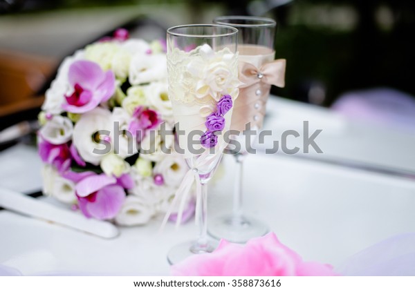 Wedding wine glasses decorated with  flowers of\
lilac with a bouquet
