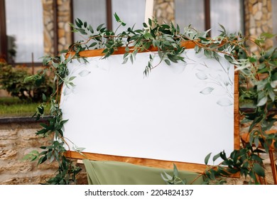 Wedding Wooden Board, Mockup, Invitation Easel, With White Space For An Inscription, Decorated With Fresh Greenery And Green Cloth. Wedding Frame Outdoors. Festive Decor, Copy Space